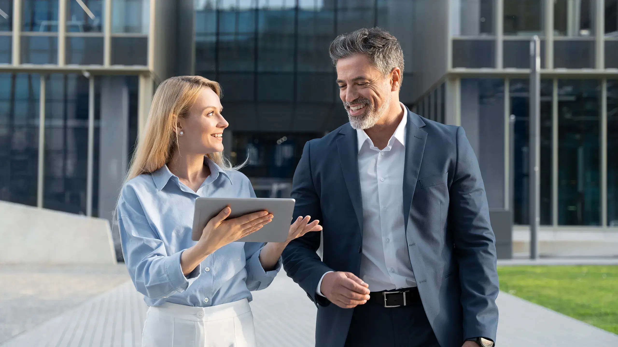 financial-woman-and-man-walking-outside-discussing-tablet
