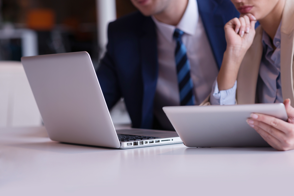 Zwei Mitarbeitende arbeiten an ihren Laptops.